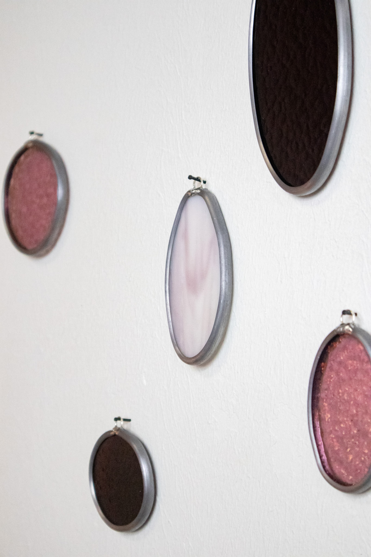 Detail van de roze glas-in-lood muurhangers op de witte muur