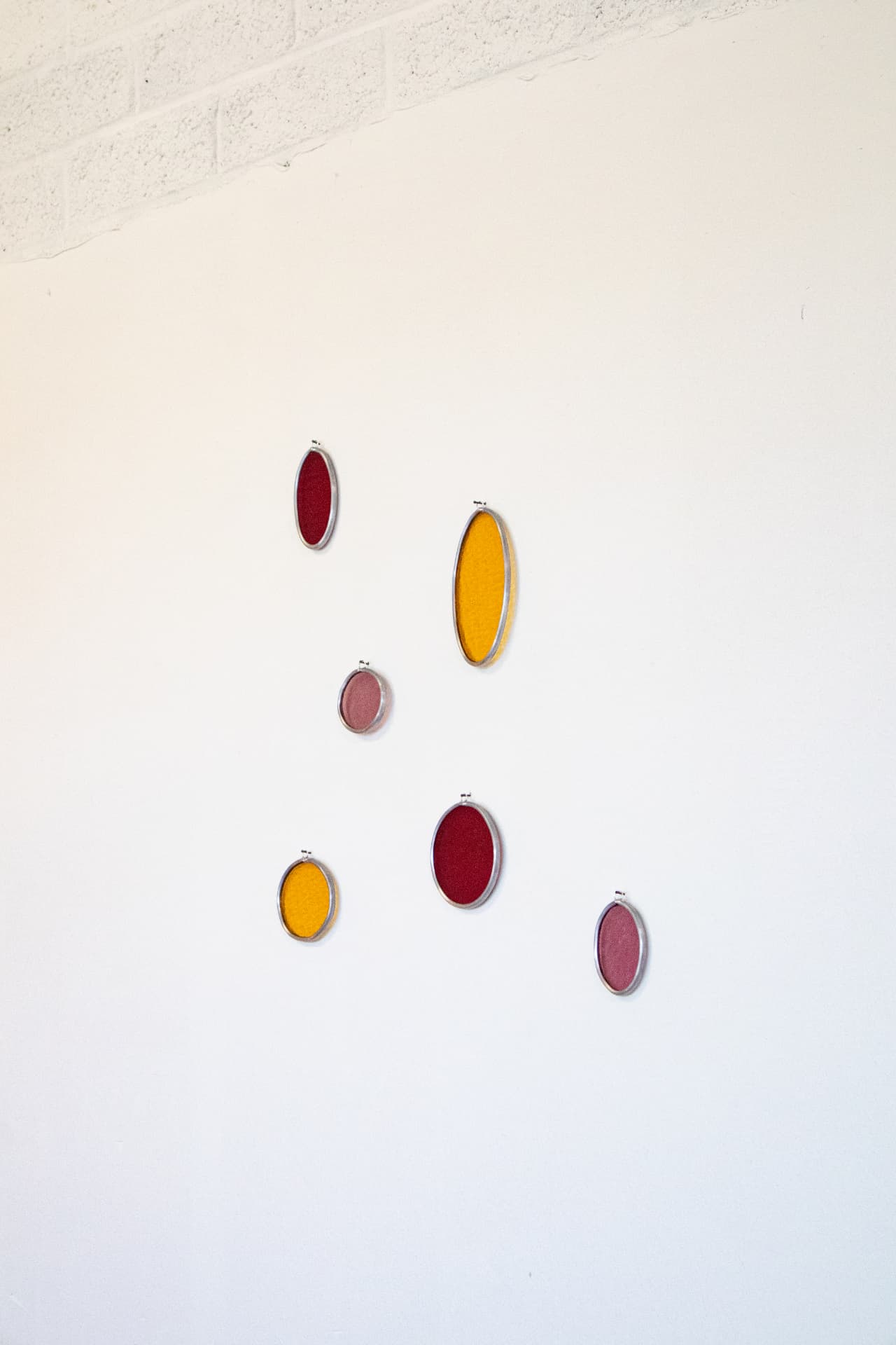 Ovale glas-in-lood wandobjecten in rood, oranje en oudroze