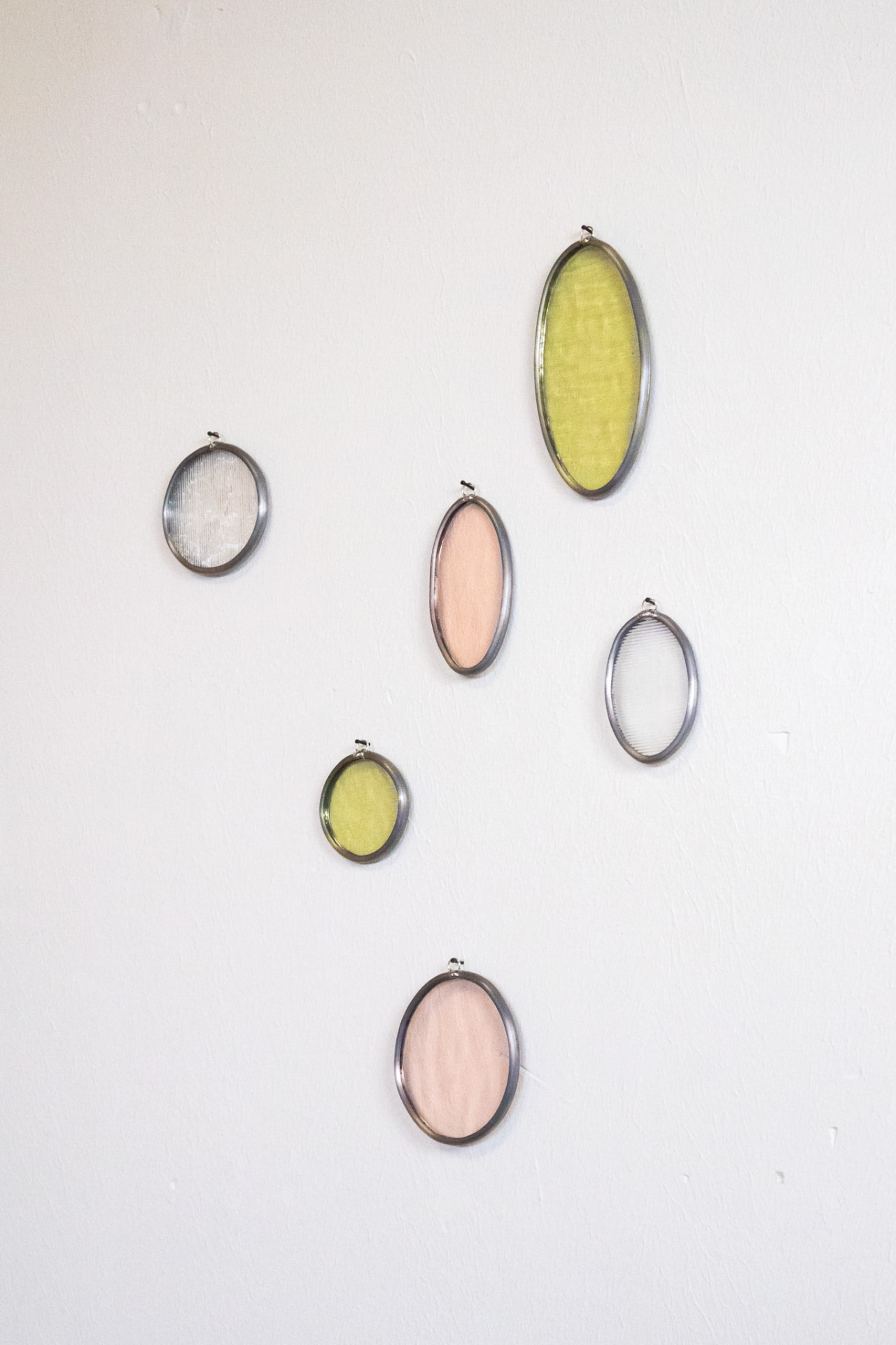 Zes ovale glas-in-lood muurhangers in roze, groen en transparant glas