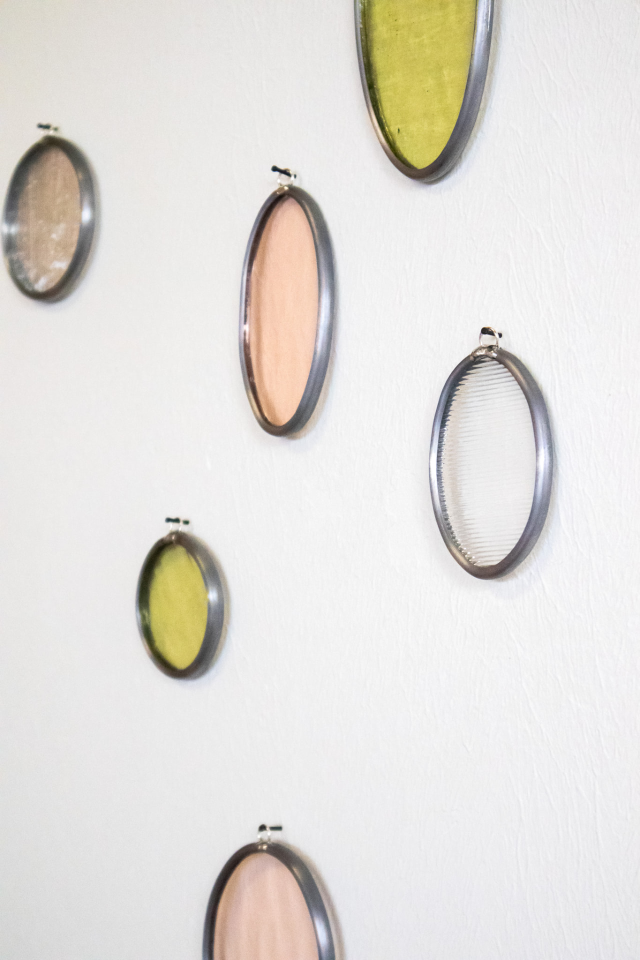 Detail van de ovale glas-in-lood muurhangers op de witte muur