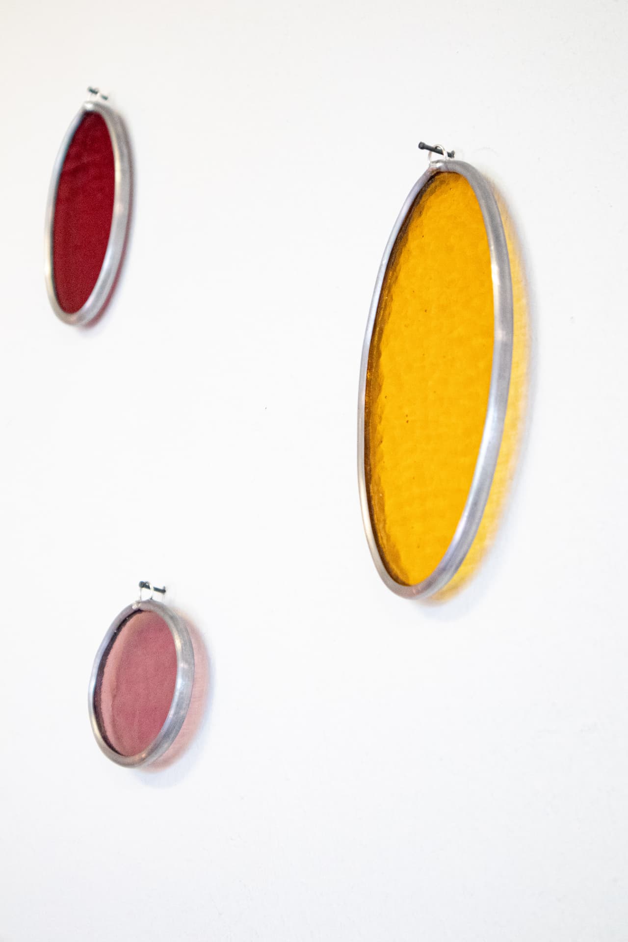Detail van de ovale glas-in-lood wandobjecten in rood en oranje