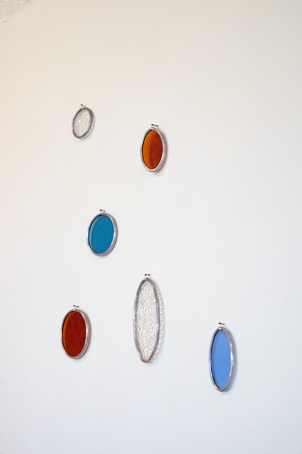 Ovale glas-in-lood druppels aan de muur in blauw and oranje