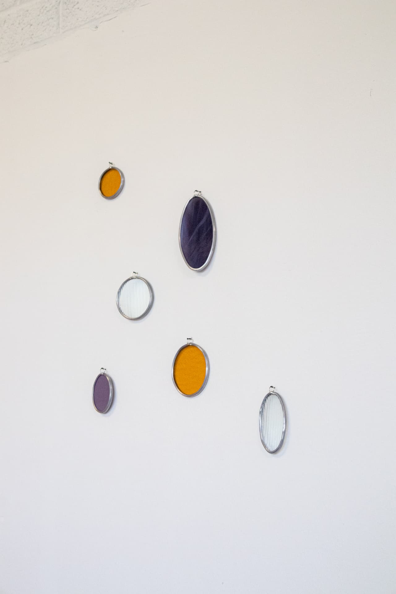 Ovale glas-in-lood wandobjecten in paars, oranje en ribbelglas